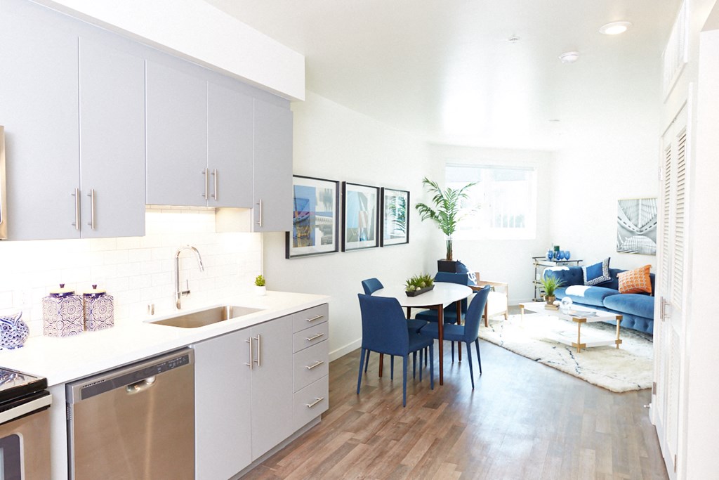 a kitchen and living room with white cabinets and a table and chairs