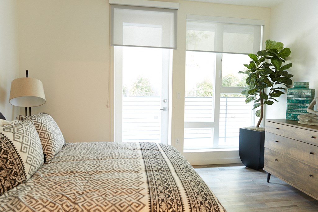 a bedroom with a bed and a window and a plant