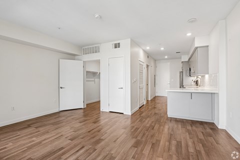 A kitchen area with white cabinets and a wooden floor.