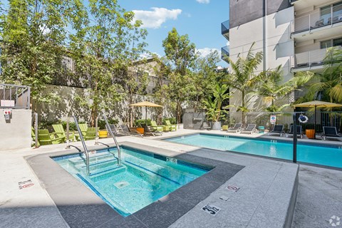 A swimming pool surrounded by trees and chairs.