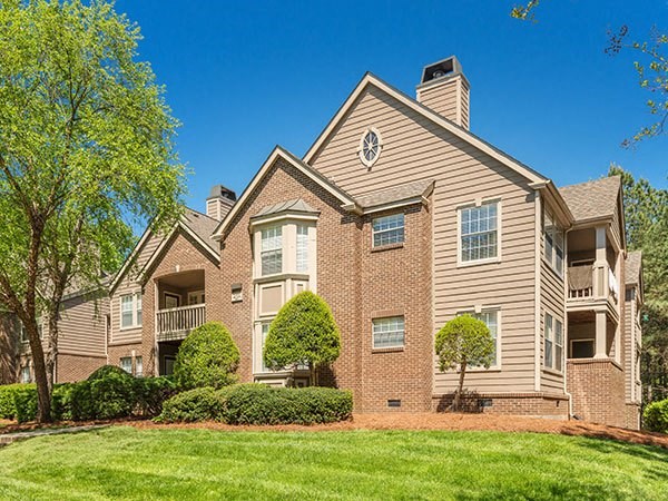a brick apartment building with trees and grass