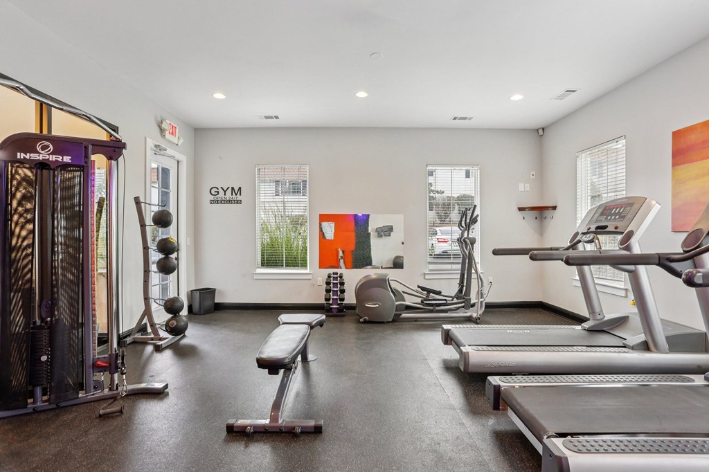 A gym with treadmills, weights, and exercise equipment.