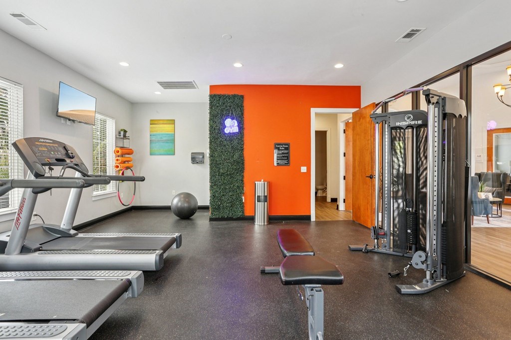 A gym with orange walls and a variety of equipment.