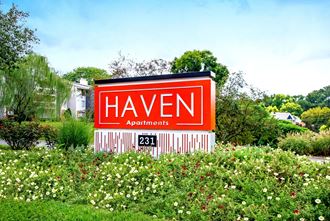 the sign for heaven apartments in front of a garden
