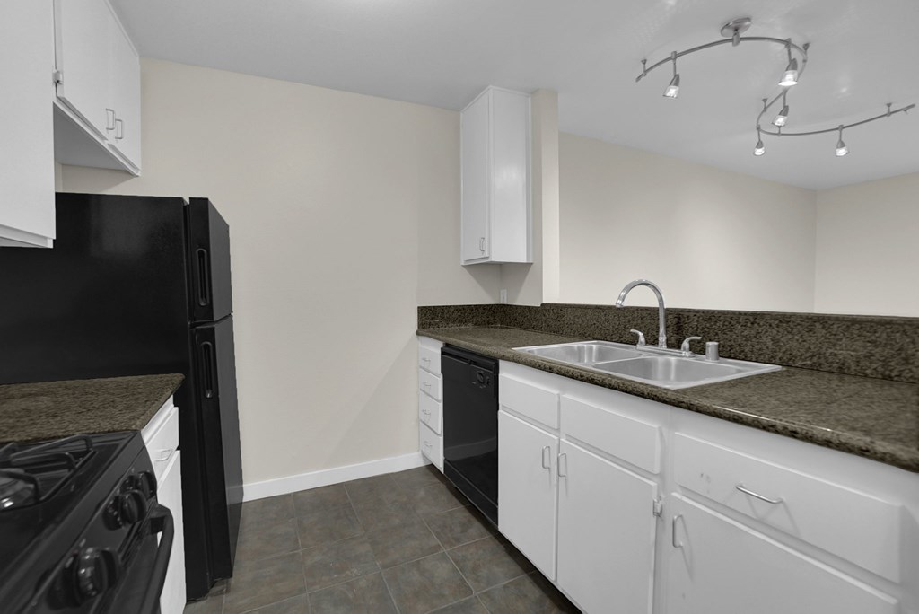A kitchen with black appliances and white cabinets.