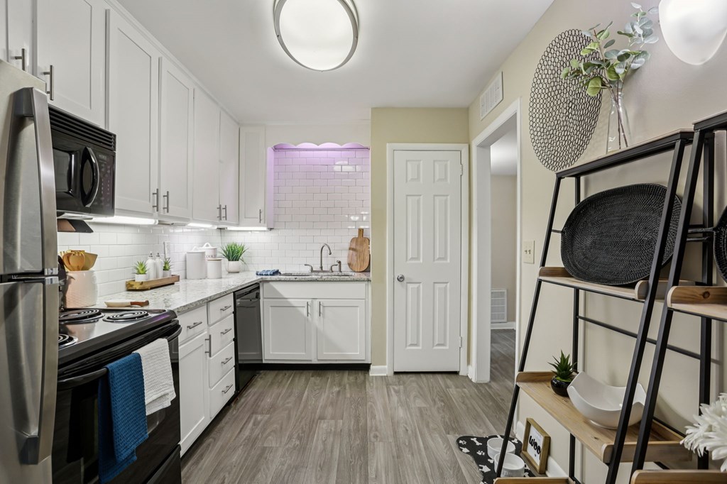 A kitchen with white cabinets and a black fridge.