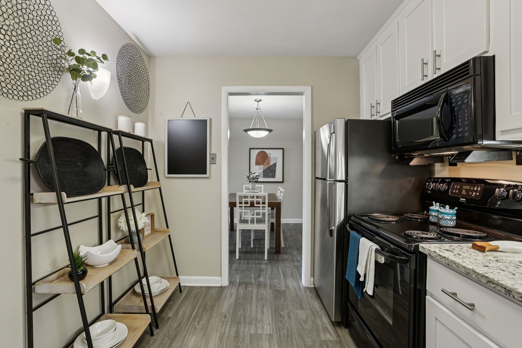 A kitchen with black appliances and white cabinets.