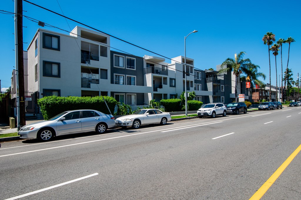 a city street with cars parked in front of an apartment building
