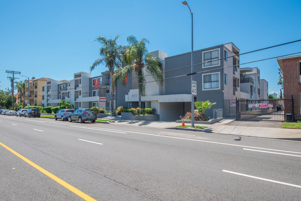 a row of apartment buildings with palm trees on a city street
