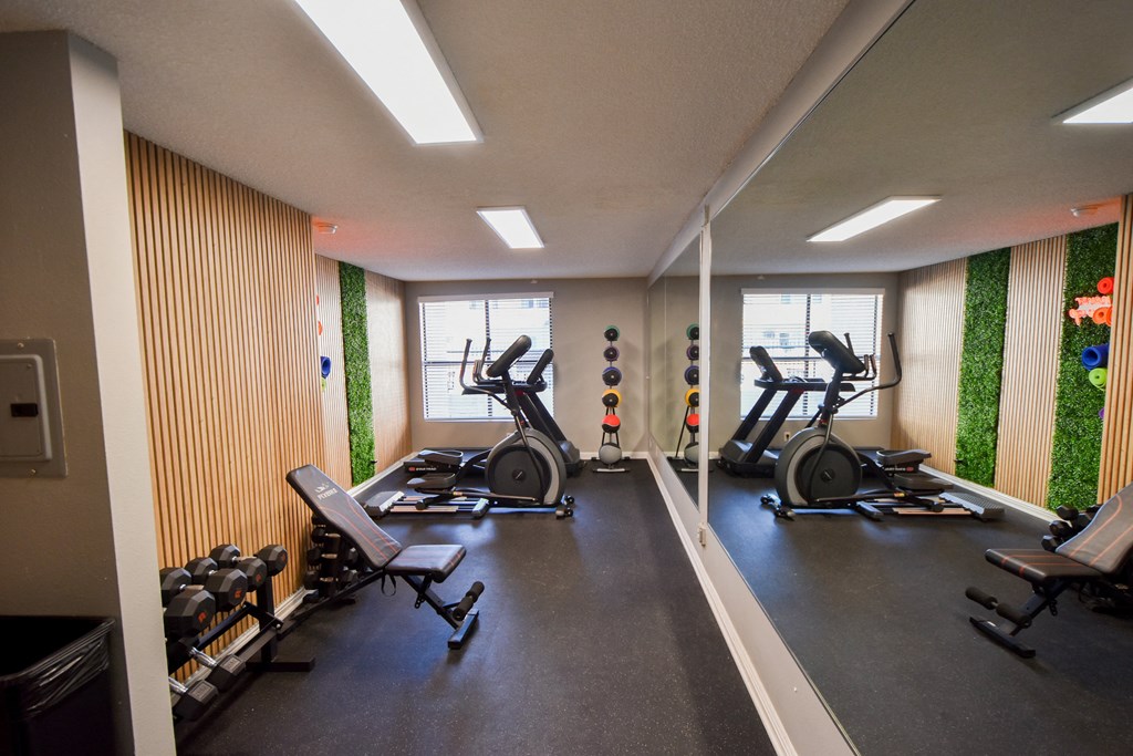 a gym with cardio machines and weights on the floor