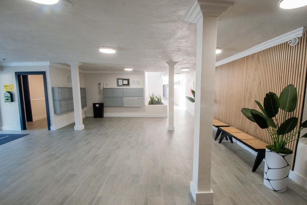 the lobby of a building with a wood floor and a wooden bench