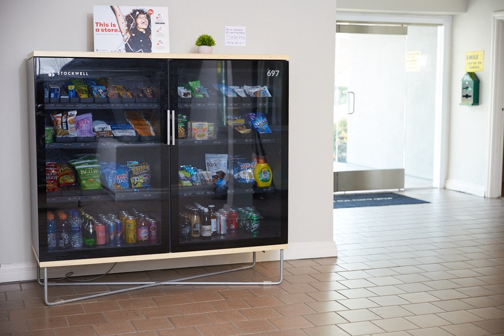 a refrigerated vending machine with household items in the leasing office lobby