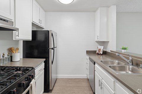 A kitchen with a black refrigerator and white cabinets.