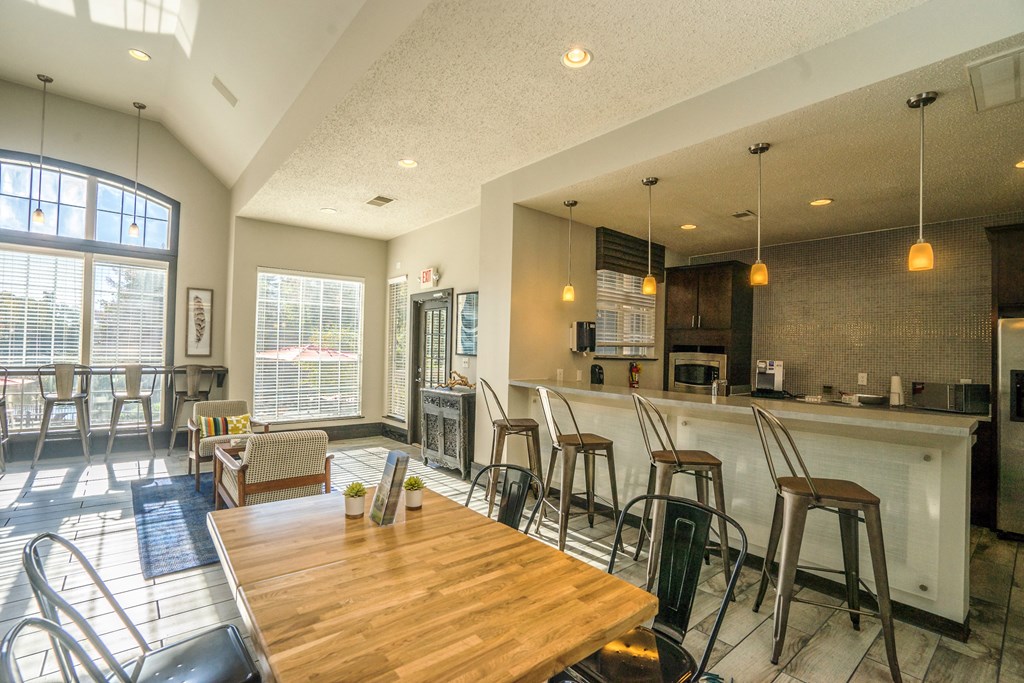 a dining room with a bar and a kitchen with a table and chairs