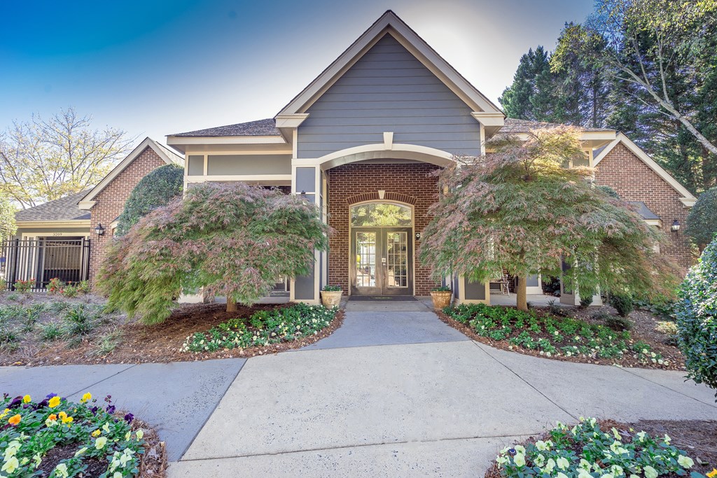 the front of the clubhouse with a walkway and two trees
