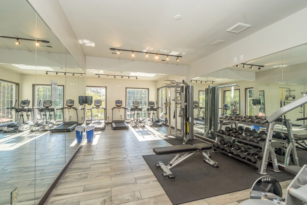 a gym with cardio equipment and mirrors on the wall