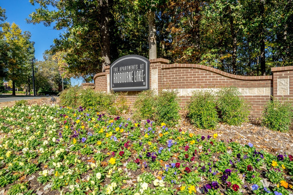 a sign in front of a brick wall with flowers