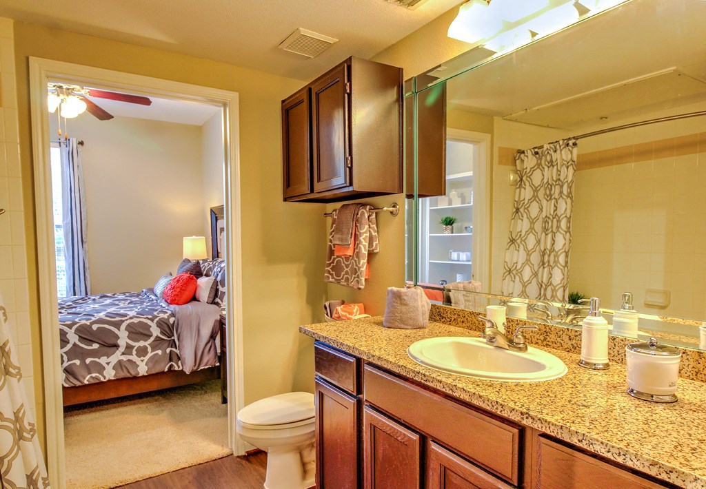 a bathroom with a sink and a toilet and a mirror at Stone Creek at Old Farm Apartments, Houston, TX 77063