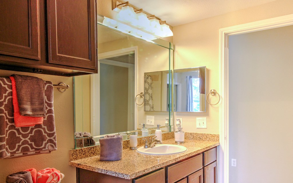 a bathroom with a sink and a mirror at Stone Creek at Old Farm Apartments, Houston, TX 77063