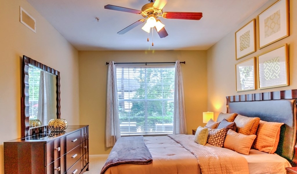 a bedroom with a large bed and a ceiling fan at Stone Creek at Old Farm Apartments, Texas
