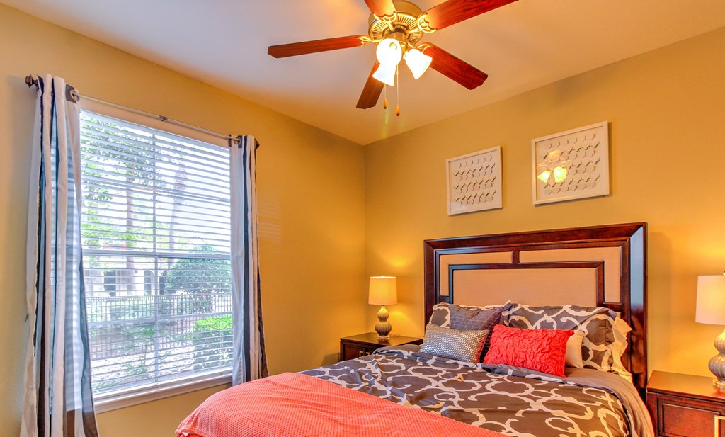 a bedroom with a large window and a ceiling fan at Stone Creek at Old Farm Apartments, Houston