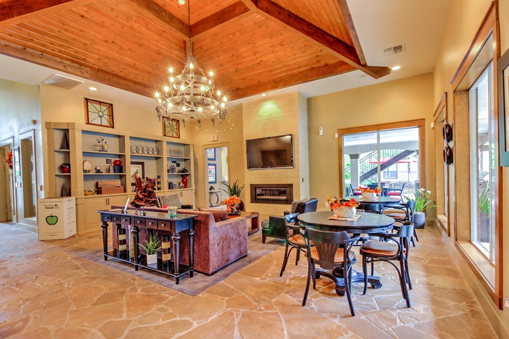 a dining room and living room with a table and chairs and a fireplace at Stone Creek at Old Farm Apartments, Houston, Texas