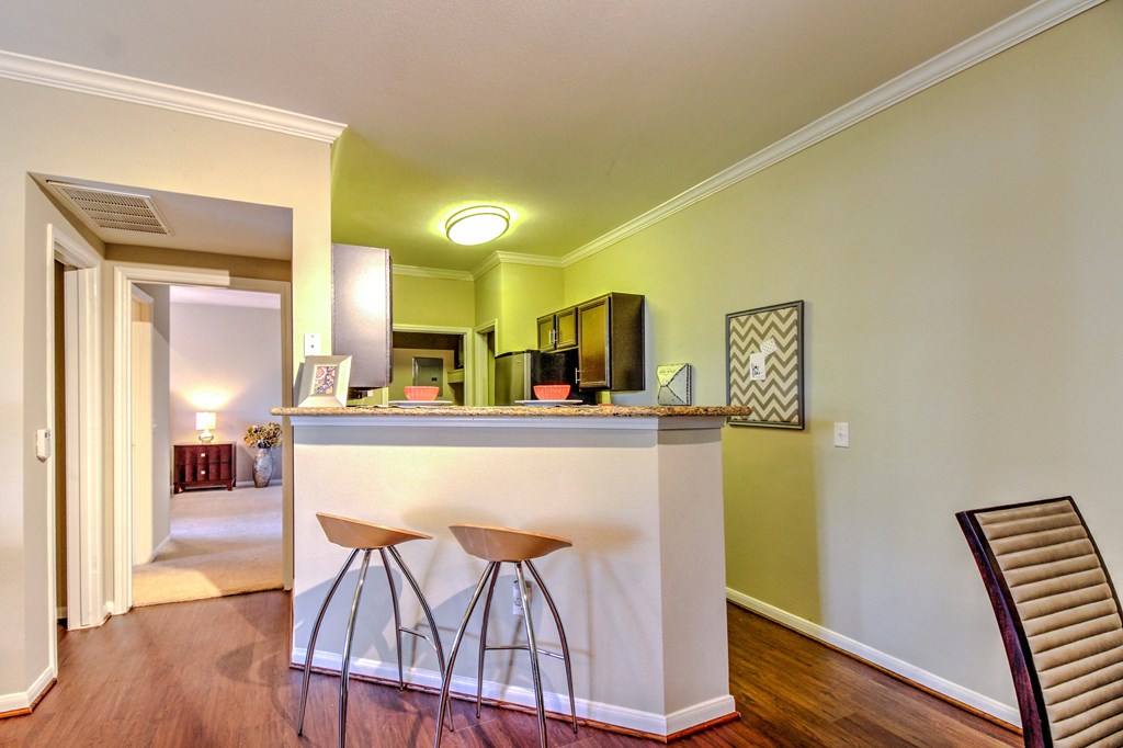 a living room with a bar with three stools at Stone Creek at Old Farm Apartments, Houston, TX