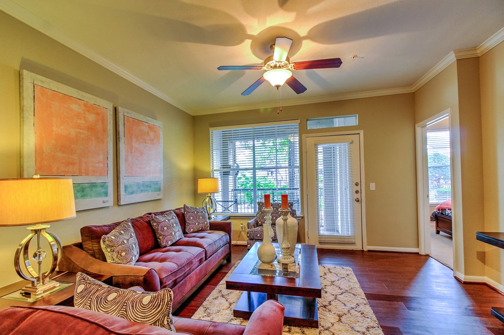 a living room with a ceiling fan and couches at Stone Creek at Old Farm Apartments, Texas