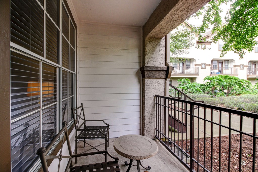 a balcony with a table and two chairs on it at Stone Creek at Old Farm Apartments, Houston, 77063