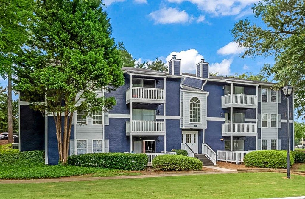 a blue and white apartment building with trees in front of it