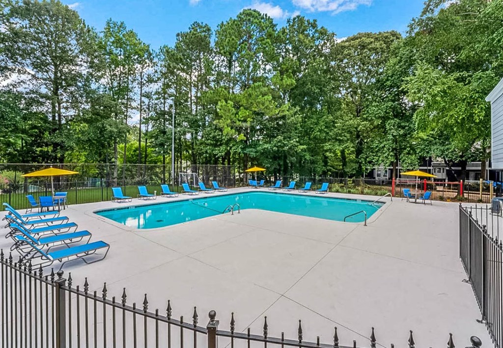 a swimming pool with chaise lounge chairs and trees in the background