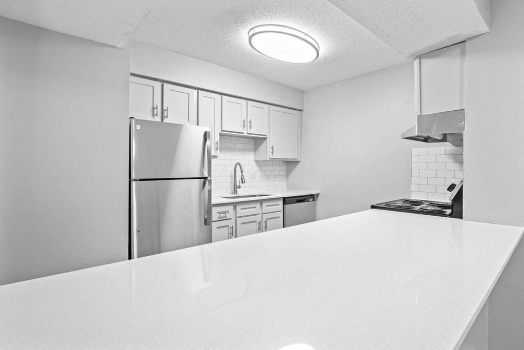 a kitchen with a white counter top and a stainless steel refrigerator