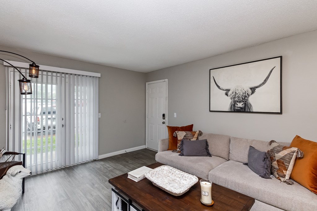 A living room with a grey couch and a painting of a bull on the wall.