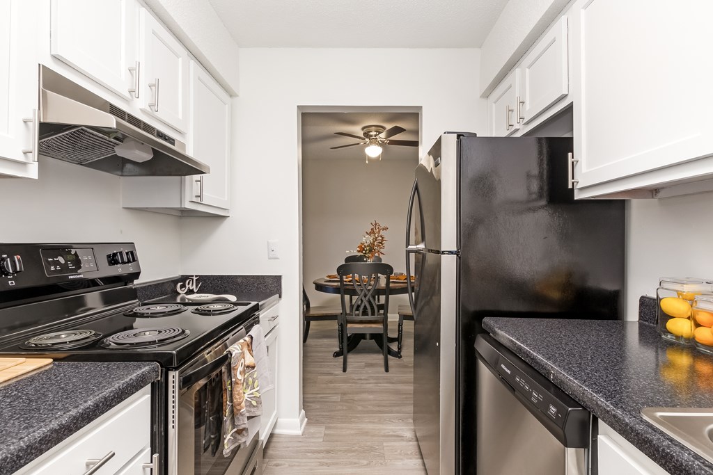A kitchen with black appliances and white cabinets.
