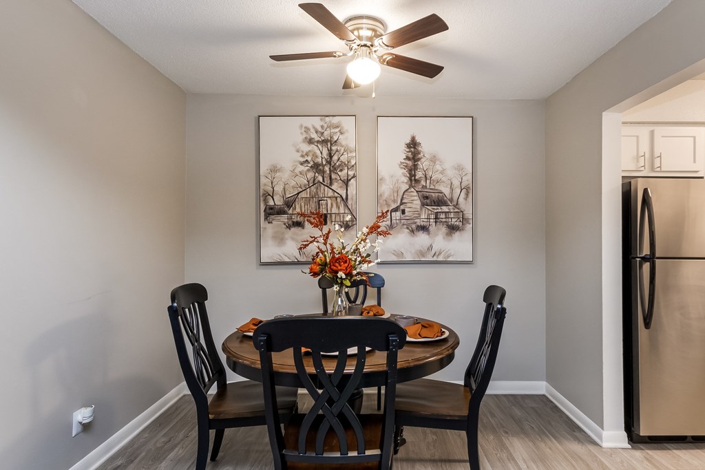 A dining room with a table set for two and a framed picture on the wall.