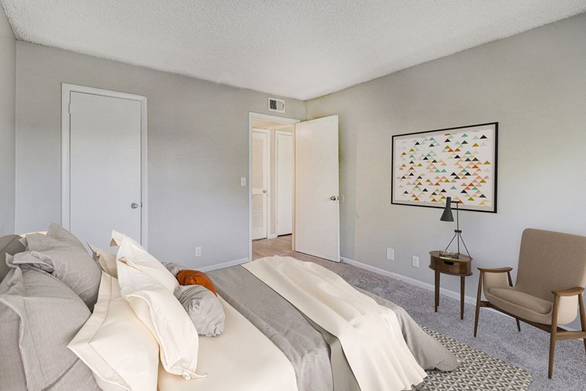 a bedroom with a bed and a chair and a door to a bathroom