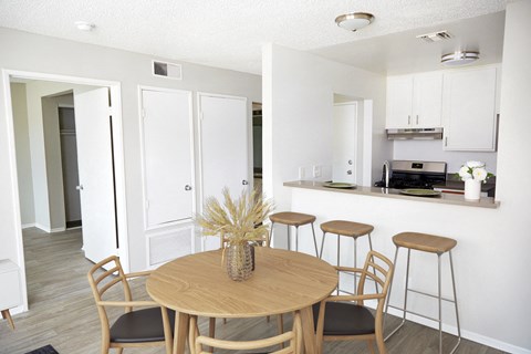 a dining room and kitchen with a table and stools