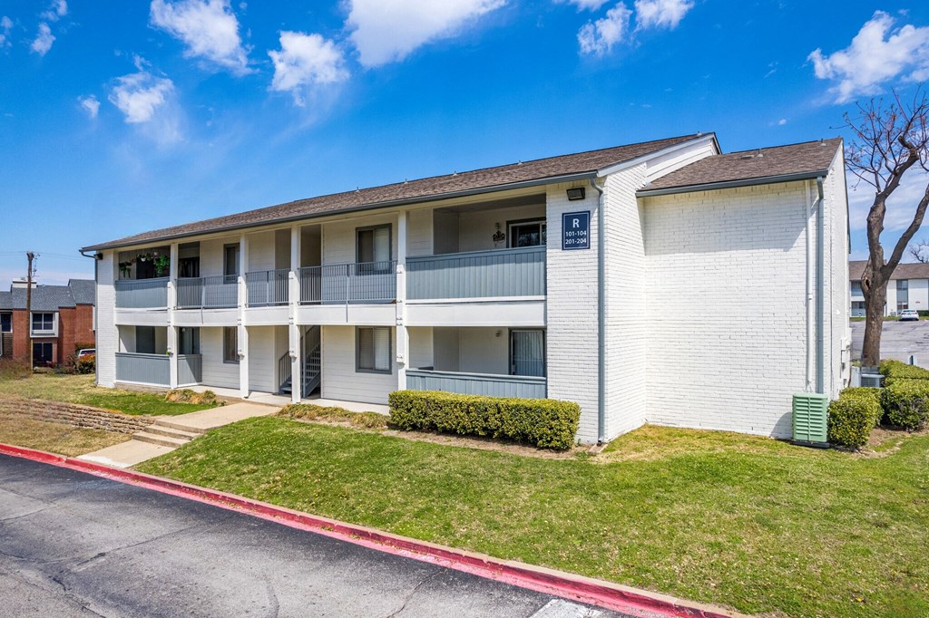 a white apartment building with balconies and a sidewalk at The Hudson, Carrollton Texas?