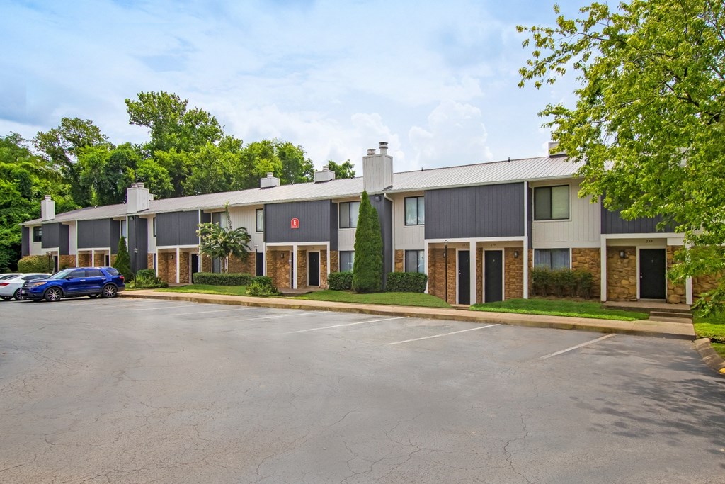 the view of a apartment building with a parking lot and trees