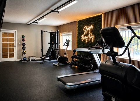 A home gym with a treadmill, weights, and exercise equipment.