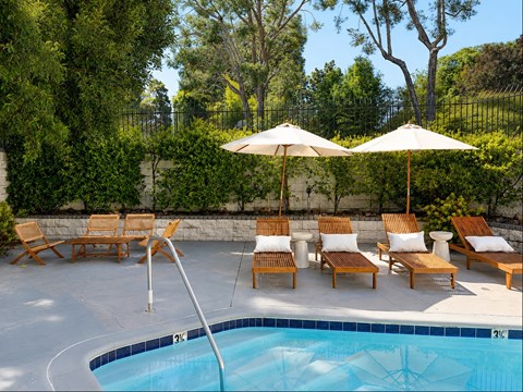 A pool with a diving board and lounge chairs.