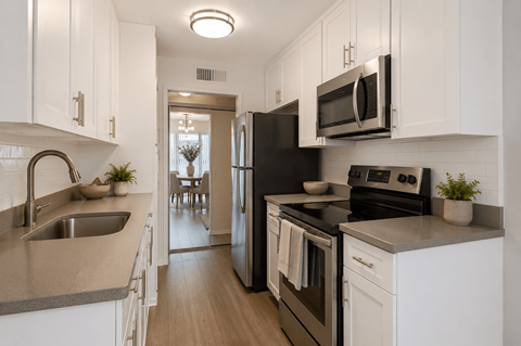 A kitchen with white cabinets and black appliances.