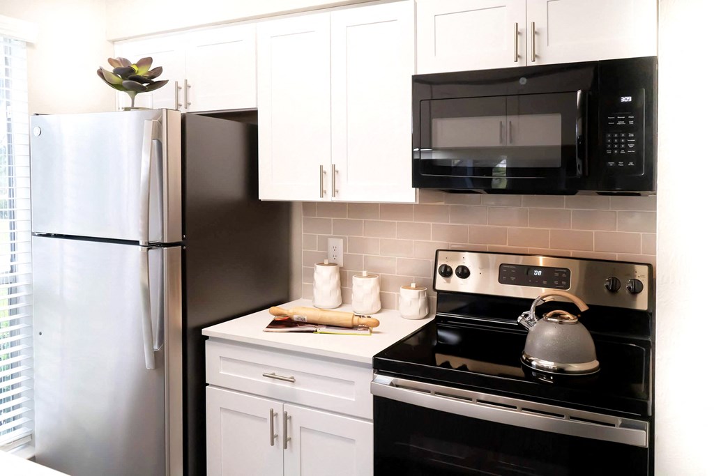 a kitchen with white cabinets and black appliances and a refrigerator a kitchen with white cabinets and black appliances and a refrigerator at Keller Oaks, Carrollton Texas?