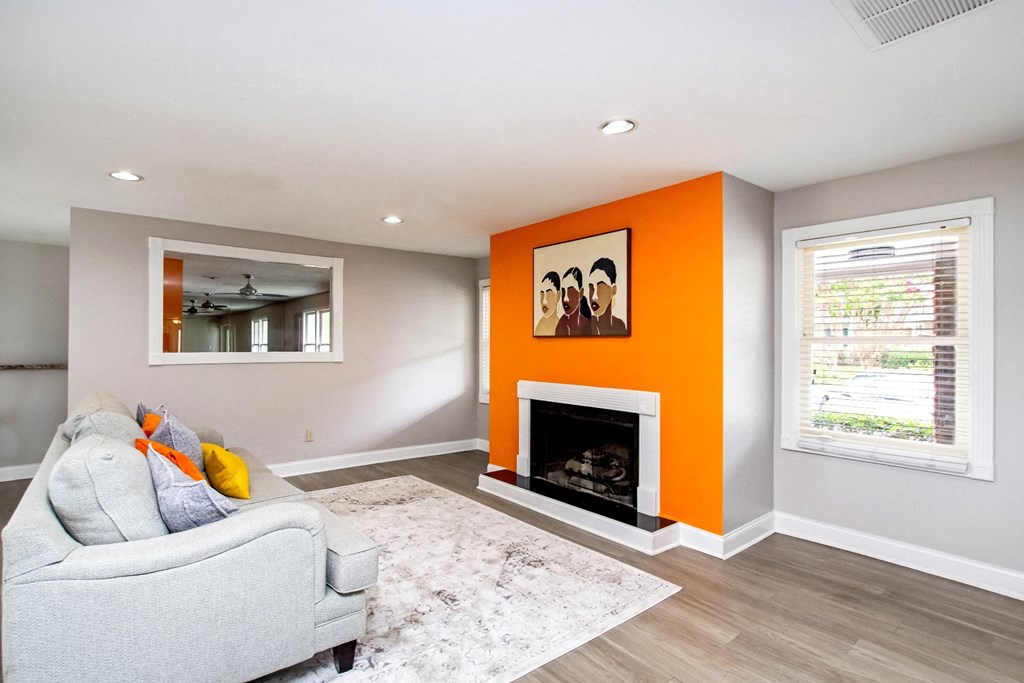 a living room with an orange accent wall and a fireplace