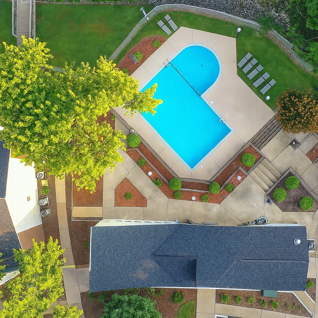 A swimming pool surrounded by a brick wall and trees.