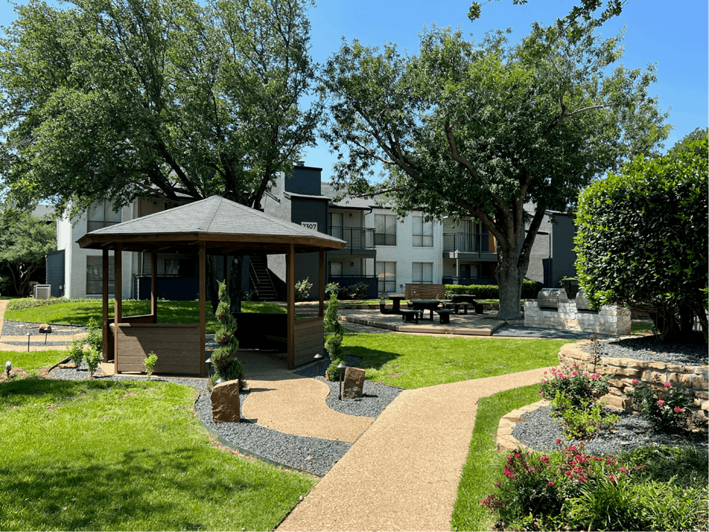 a park with a gazebo and trees in front of an apartment building at District 2308, Texas 