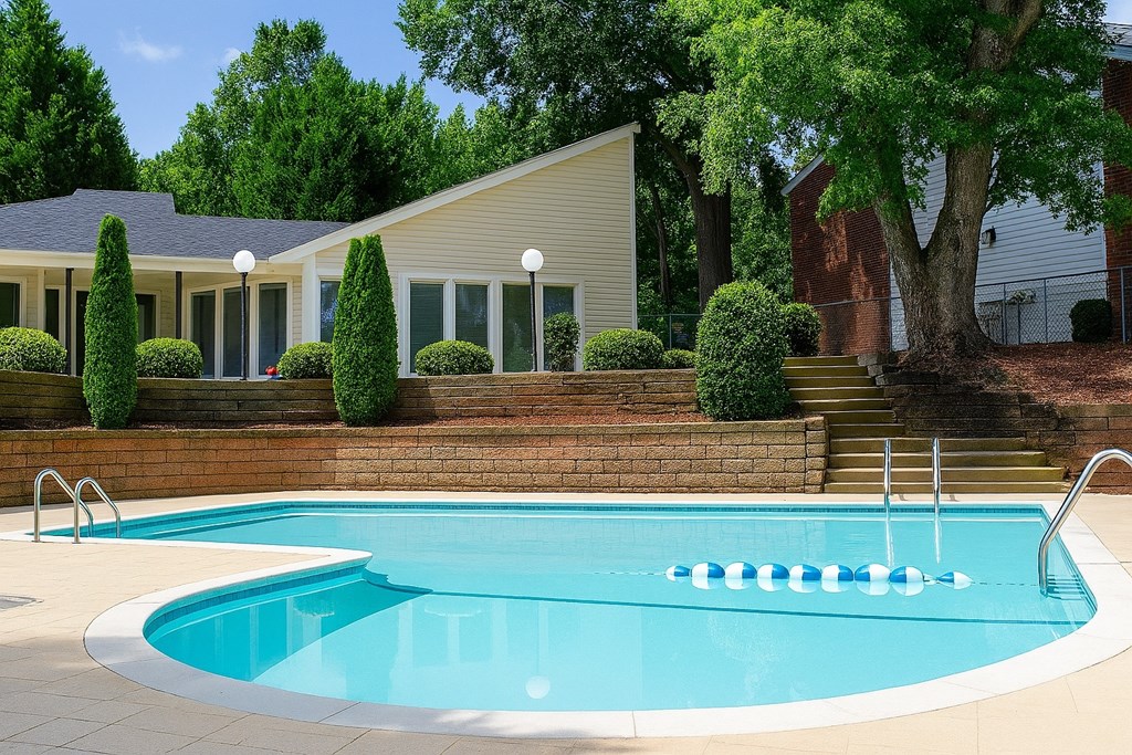 A swimming pool in front of a house with a tree.