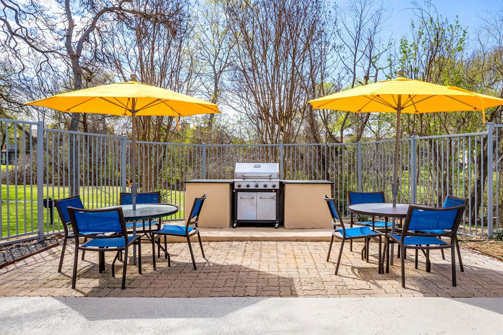a patio with yellow umbrellas and tables with chairs and a grill at The Hudson, Texas ?