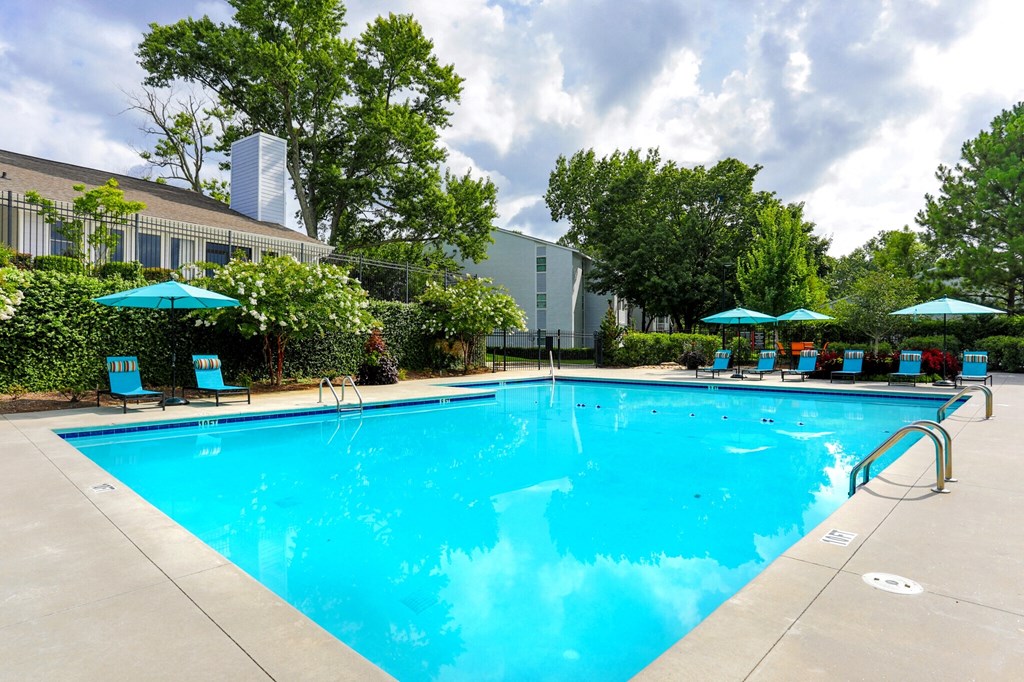 a swimming pool with chairs and umbrellas in front of a building