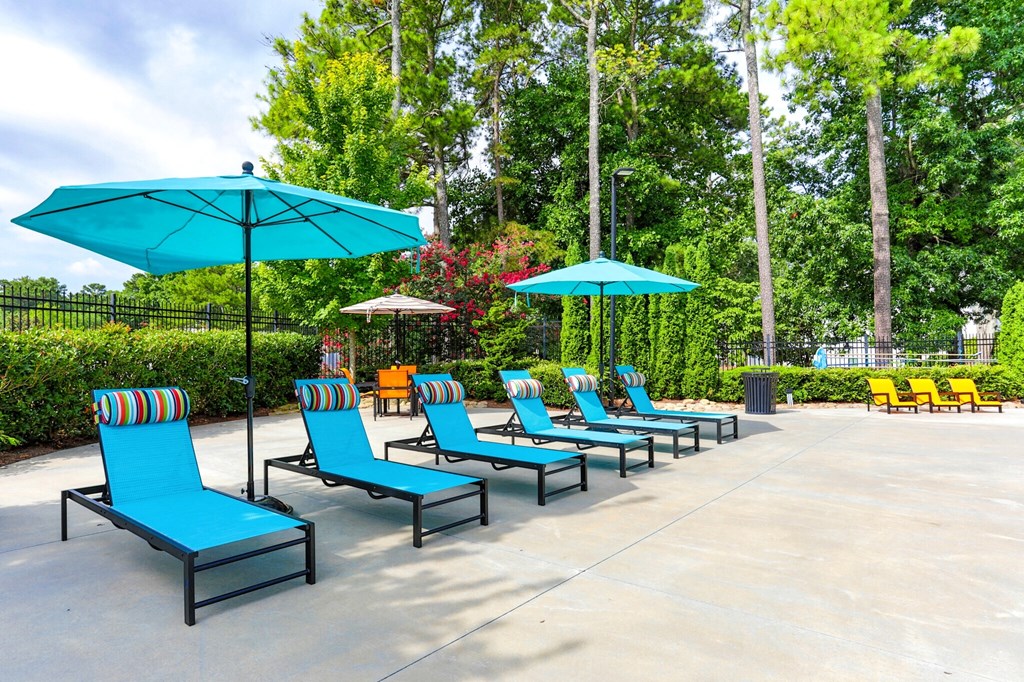 a row of blue lounge chairs with umbrellas in a park